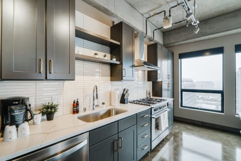 Modern kitchen with dark cabinets and a view outside.