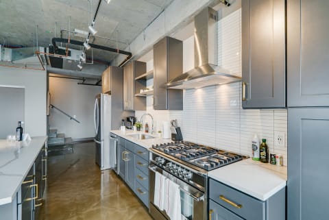 Modern kitchen with grey cabinets, stainless steel appliances, and polished concrete floors.
