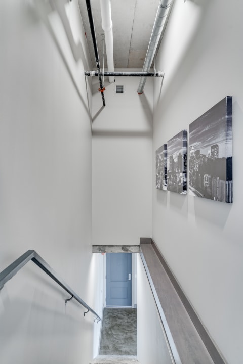 A minimalist staircase with exposed pipes and urban-themed wall art.