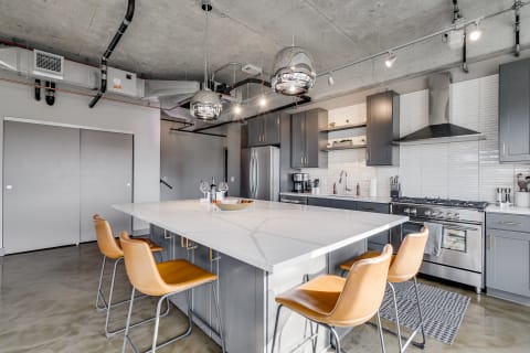 Contemporary kitchen with marble island, gray cabinets, and industrial accents.