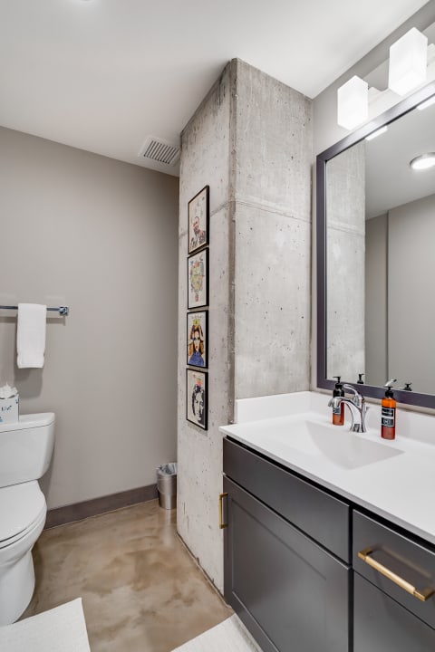 Interior view of a modern bathroom with a concrete column, framed artworks, and contemporary fixtures.