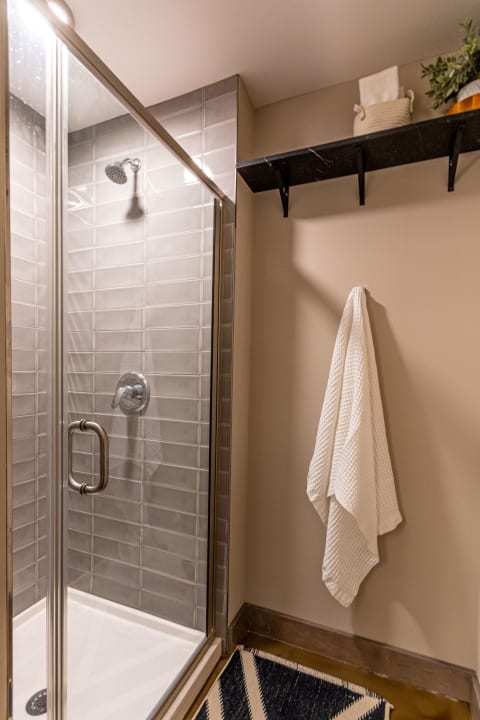 Modern shower enclosure with gray tiles and a hanging white towel.