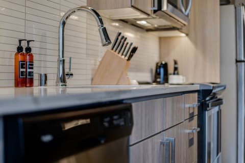 Modern kitchen featuring a stainless steel faucet, amber bottles, and a knife block on a white countertop.