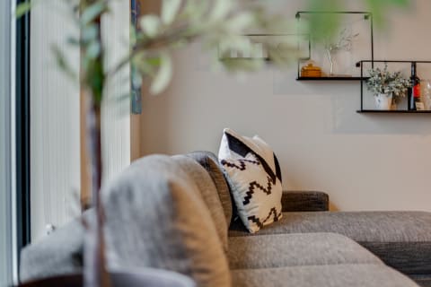 A modern living room corner featuring a gray sectional sofa and decorative wall shelf.