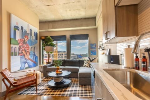 Modern living area featuring a large art piece, sectional sofa, and city views.