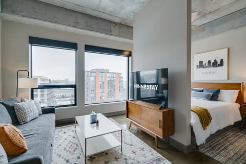 Interior view of a modern studio apartment with urban landscape outside.