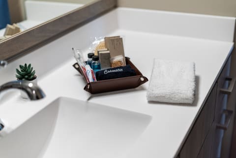 A bathroom countertop with a brown tray of toiletries and a folded white towel.