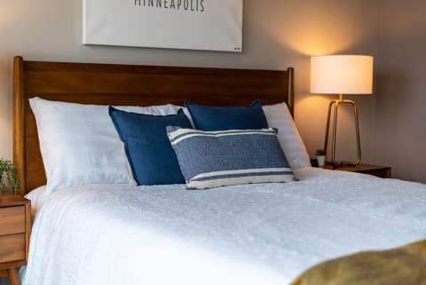 A neatly made bed with navy decorative pillows and a stylish lamp in a cozy bedroom.