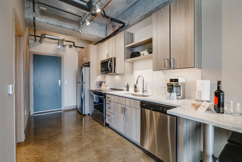 Stylish modern kitchen featuring wood cabinets, stainless steel appliances, and a polished countertop.