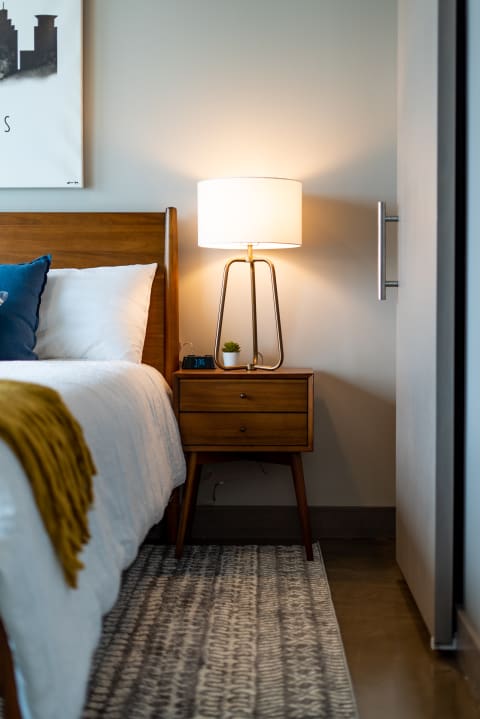 Cozy bedroom corner with a wooden bed, nightstand, and table lamp.