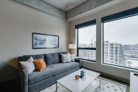 Contemporary living room featuring a gray sofa, decorative pillows, and large windows with city views.