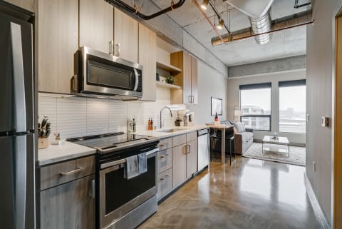 Contemporary kitchen with gray and wood finishes, leading to a cozy living space.