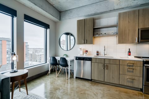 Stylish apartment kitchenette featuring modern appliances and large windows.