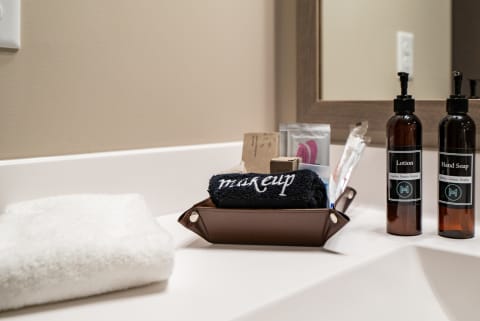 Bathroom countertop with a towel, a container of makeup items, lotion, and hand soap bottles.