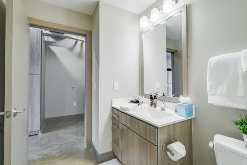 A contemporary bathroom with a vanity, modern lighting, and a neutral color scheme.