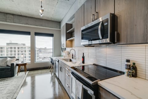 Contemporary kitchen interior featuring sleek cabinetry and urban landscape views through large windows.