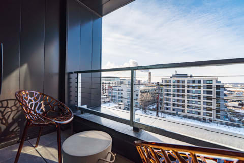 Stylish balcony with two metal chairs overlooking an urban scene with snow.