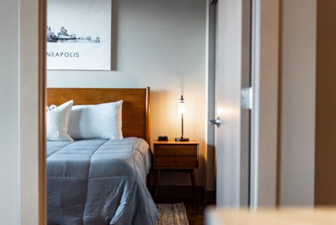 Cozy bedroom with gray bedding, a wooden headboard, and a stylish lamp.