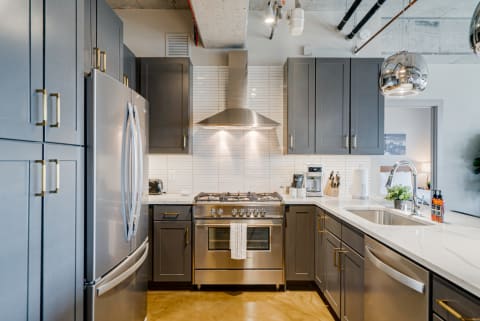 Modern U-shaped kitchen with dark cabinets, stainless steel appliances, and white countertops.
