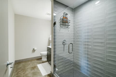 A modern bathroom featuring a glass shower enclosure and a white toilet on polished flooring.