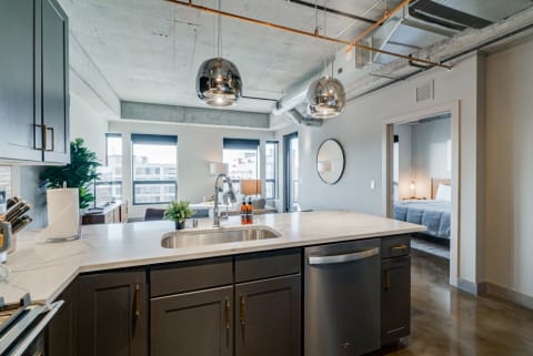 Modern kitchen featuring dark cabinets, white countertop, and large windows with an urban view.