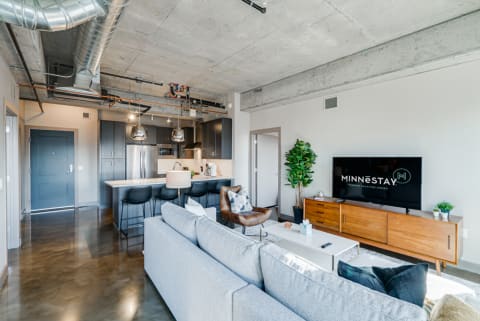 Interior view of a modern apartment featuring a living area and kitchen with industrial design elements.