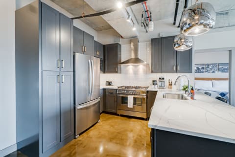 Contemporary kitchen with blue cabinets, stainless steel appliances, and polished concrete floor.