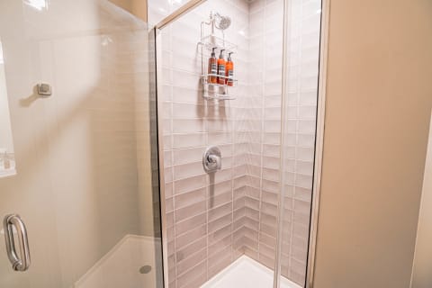 Interior view of a modern shower with gray tiles and a chrome showerhead.