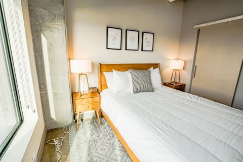 Cozy modern bedroom with double bed, wooden furniture, and botanical prints on the wall.