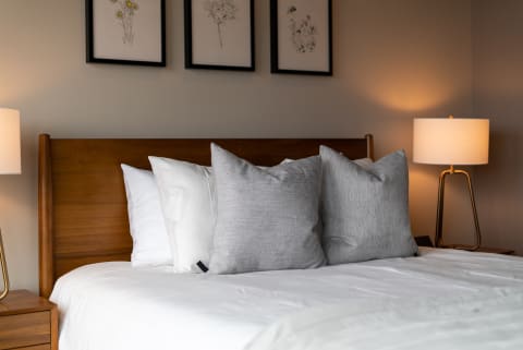 Modern bedroom with a wooden headboard and decorative pillows.