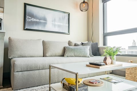 A grey sectional sofa with throw pillows in a bright living room with a coffee table and wall art.