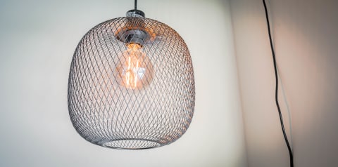 A pendant light featuring a mesh design with a warm light bulb inside.