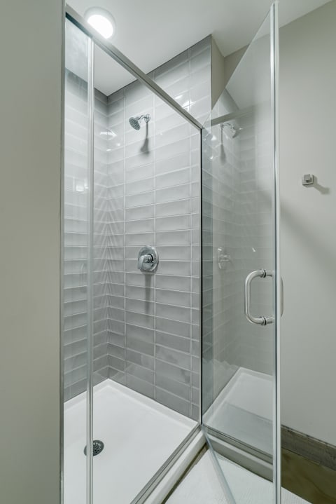 A contemporary shower enclosure with glass walls and gray tiles.