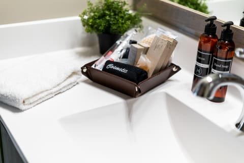 An organized bathroom countertop with a white towel, a leather basket of cosmetics, and lotion and hand soap bottles.