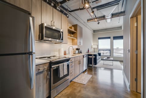 Stylish kitchen with stainless steel appliances and a cozy living area in the background.