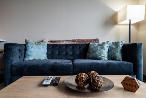 Cozy living room with a dark blue sofa, decorative pillows, and a round tray with natural orbs.
