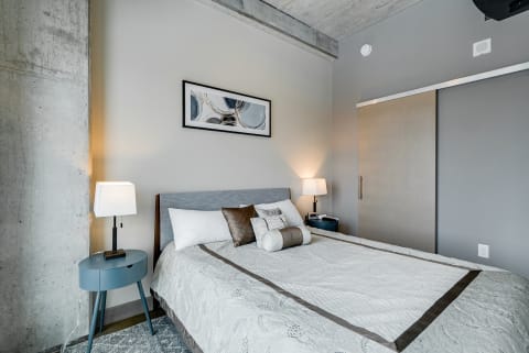 Modern bedroom with a queen bed, bedside tables, and abstract artwork.