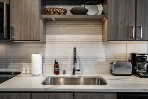 A contemporary kitchen counter featuring a stainless steel sink, modern faucet, and minimalistic decor.