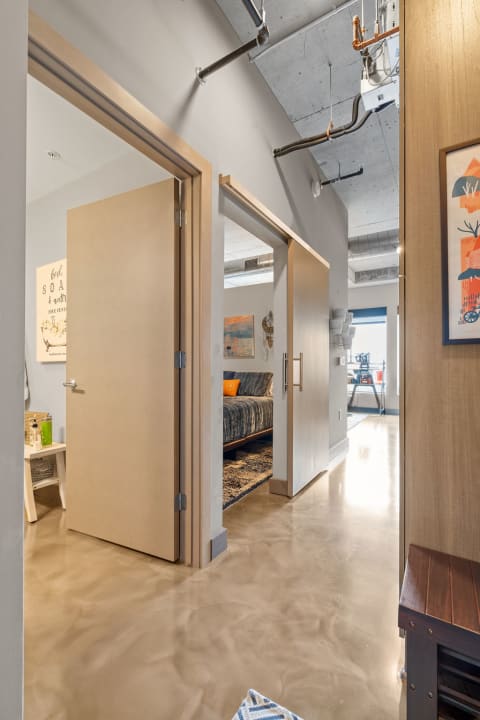 Contemporary hallway with doors and a cozy bedroom visible in the background.