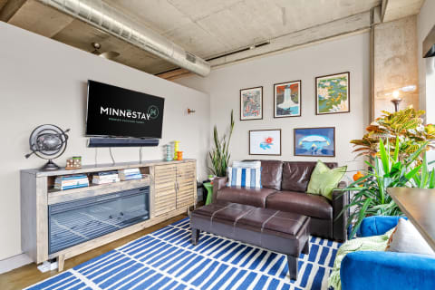 A stylish living room with a leather sofa, media console, and colorful wall art.