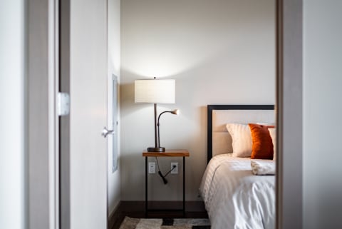 Cozy bedroom with a neatly made bed and a stylish lamp illuminating the space.