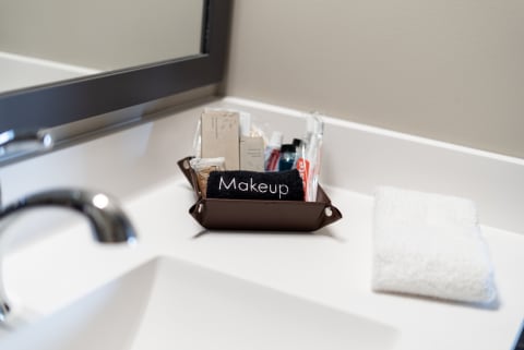 Bathroom countertop with a dark brown basket filled with makeup items and a white towel.