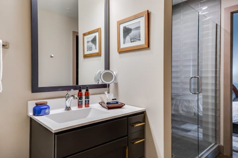 Modern bathroom featuring a dark wood vanity, a large mirror, and a glass shower.
