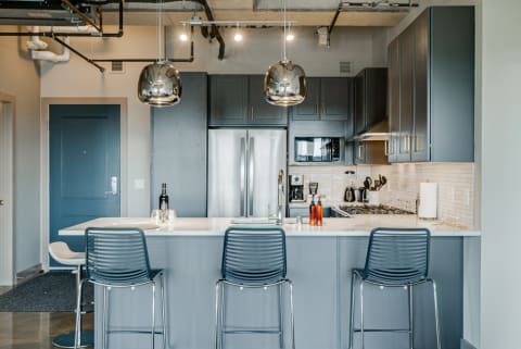 Modern kitchen featuring a marble island, stainless steel appliances, and elegant pendant lights.