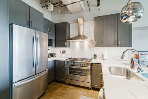 A contemporary kitchen featuring dark gray cabinets and stainless steel appliances.
