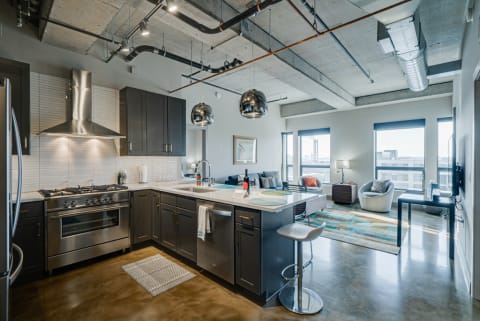 Contemporary kitchen and living area with dark cabinetry and large windows.