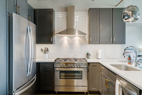 Contemporary kitchen featuring gray cabinets, stainless steel appliances, and white countertops.
