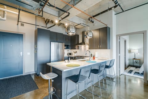 Contemporary kitchen with dark cabinets, stainless steel appliances, and bar stools.