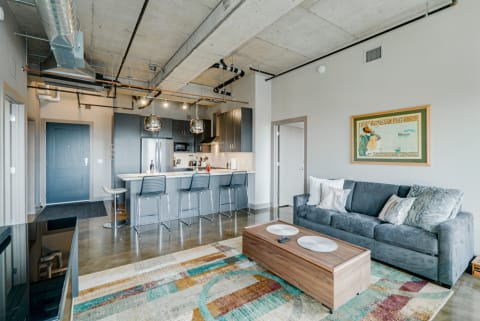 Modern living room featuring a gray sofa, wooden coffee table, and stylish kitchen.