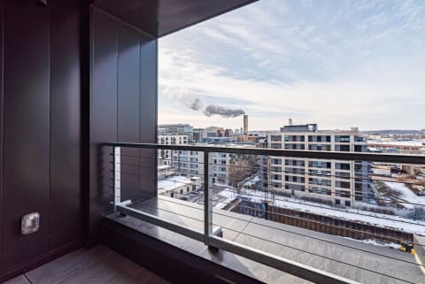 Modern balcony view overlooking an industrial urban landscape with smoky chimneys.